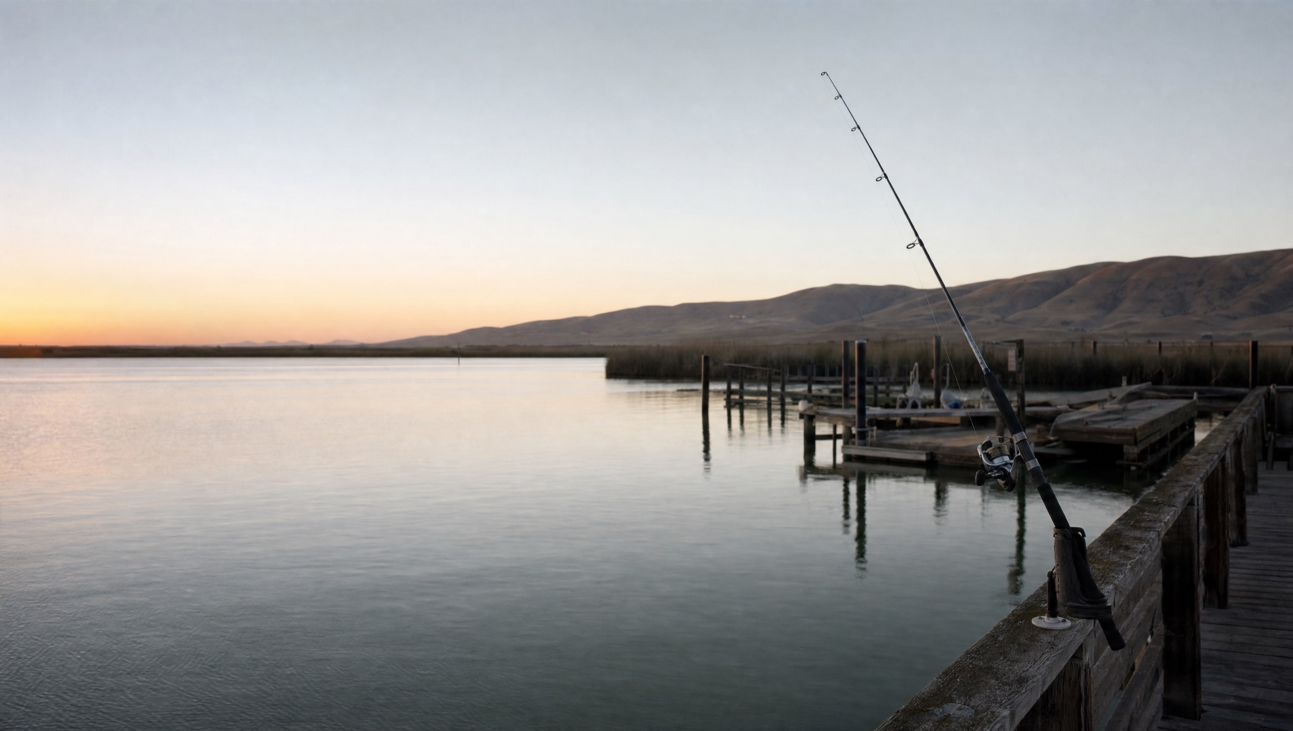 A fishing rod in a holder on a harbor dock at dawn on Suisun Bay.